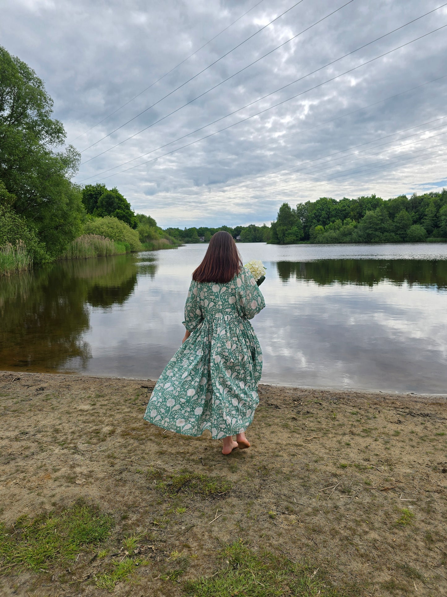 Frau im Camilla Kleid – Misty Jade am Ufer eines ruhigen Sees mit Blumenmuster und langen Ärmeln.