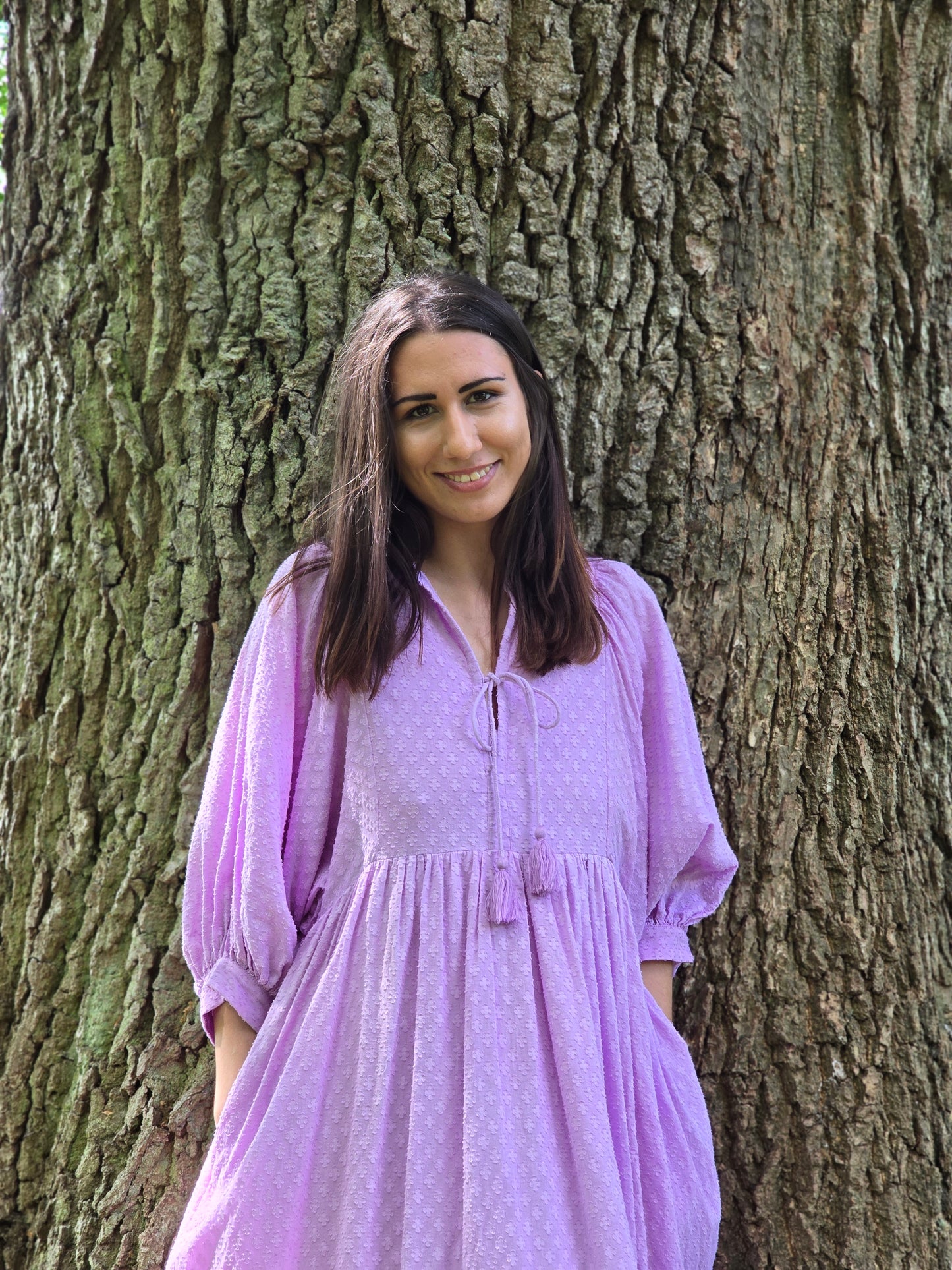 Lucia Kleid in zartem Fliederton, ideal für Alltag und warme Sommerabende, fotografiert vor einem Baum.