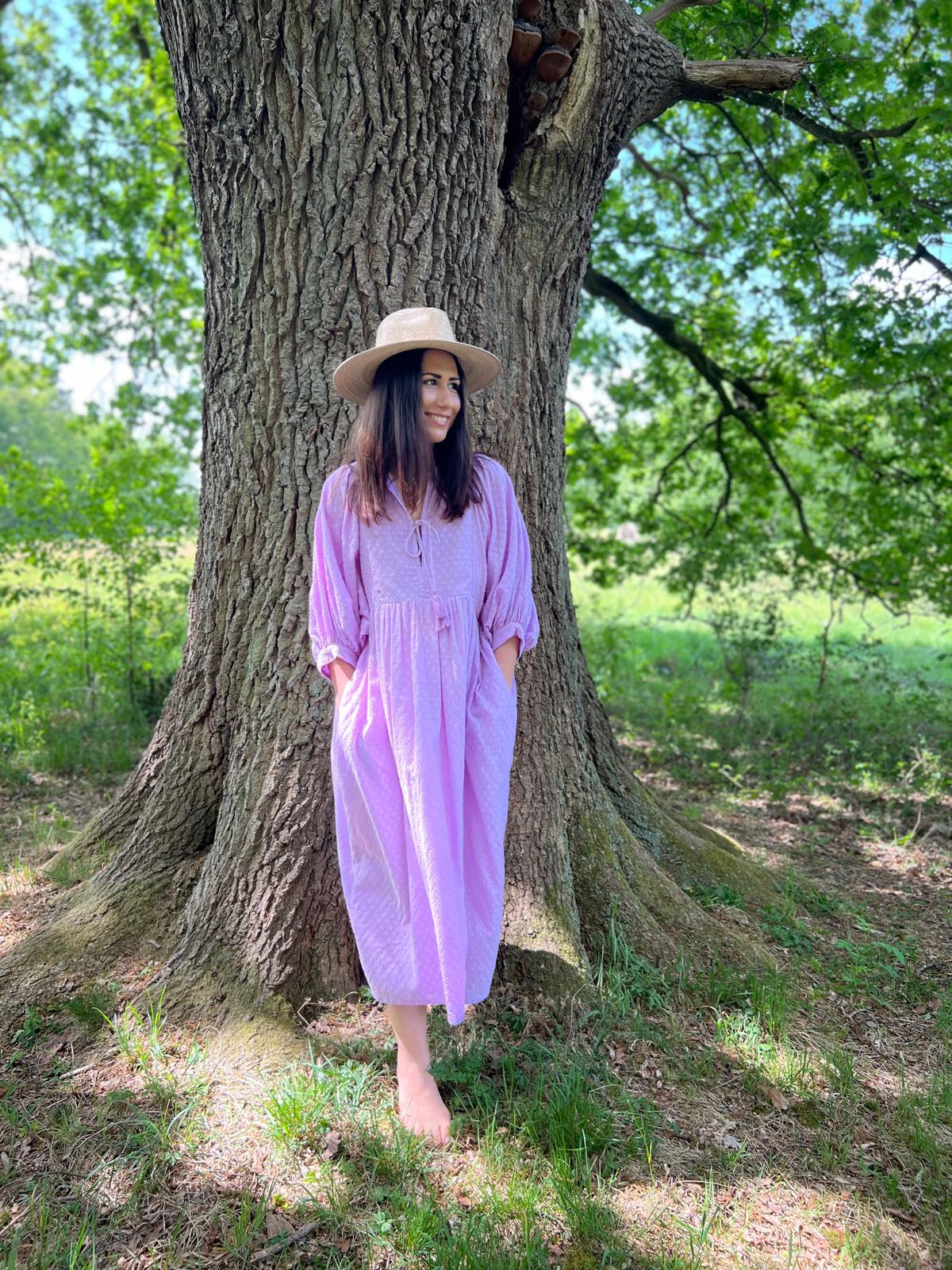 Frau im lila Midikleid Lucia unter einem Baum, passend für Alltag und Sommerabende.