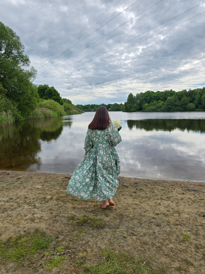 Frau im Camilla Kleid – Misty Jade am Ufer eines ruhigen Sees mit Blumenmuster und langen Ärmeln.