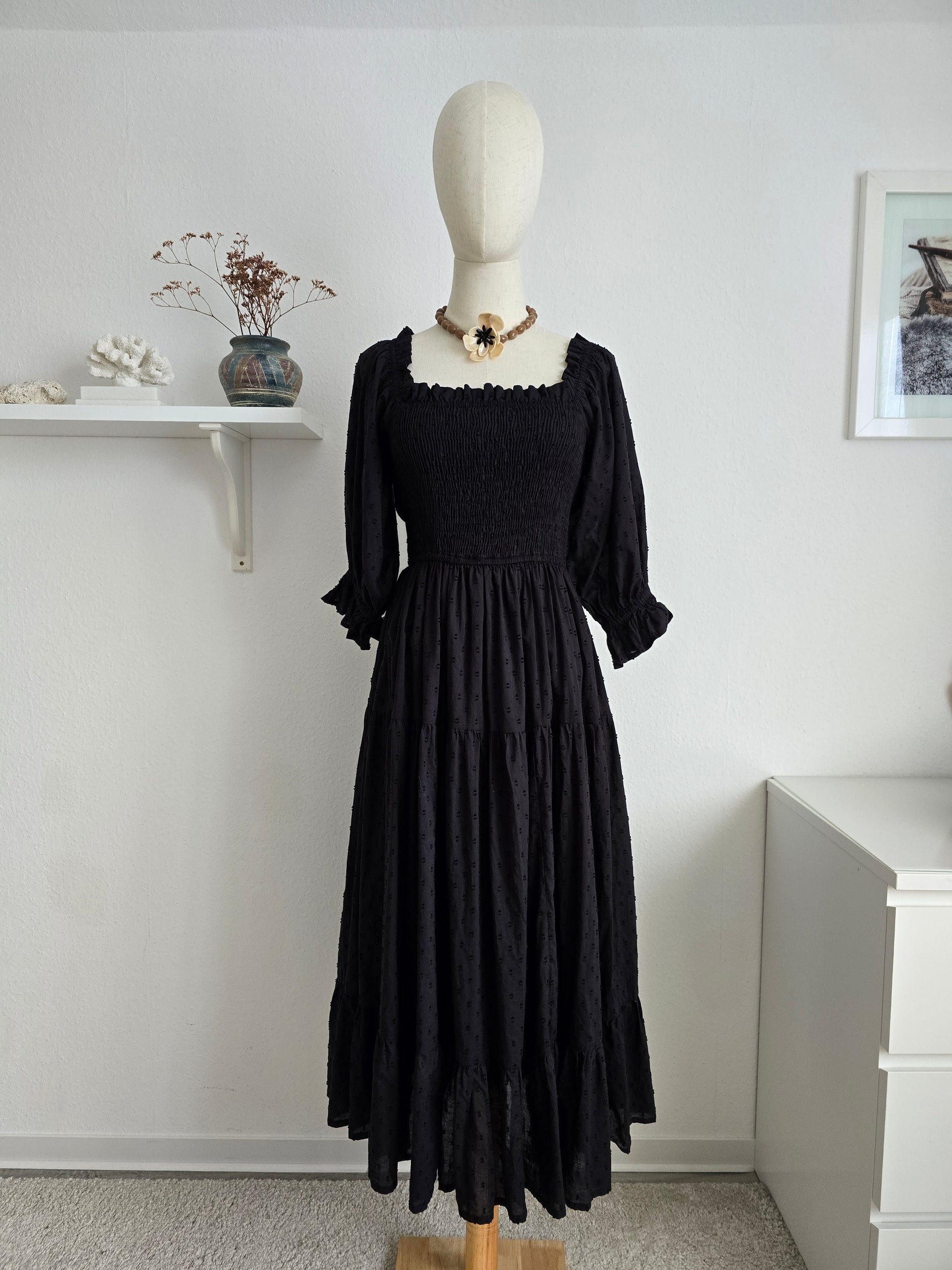 Schwarzes Midi-Kleid aus Baumwolle mit Puffärmeln und Smok-Oberteil für mühelosen, femininen Stil.