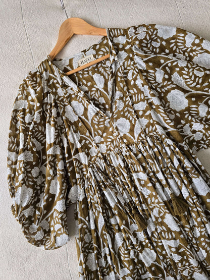 Camilla Kleid Braun mit Handblockdruck – Fließendes, Blumiges Midi-Baumwollkleid auf einem Holzkleiderbügel.