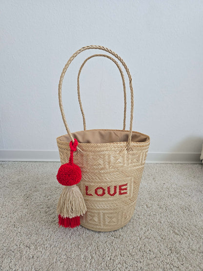Geflochtene Korbtasche in Bucket-Form mit großen Pompons
