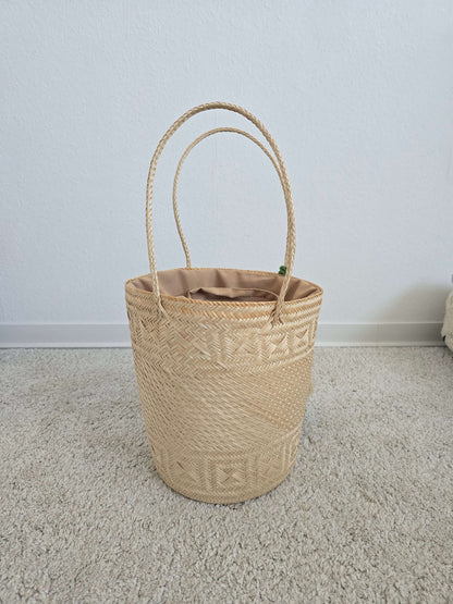 Geflochtene Bucket-Korbtasche mit auffälligen großen Pompons