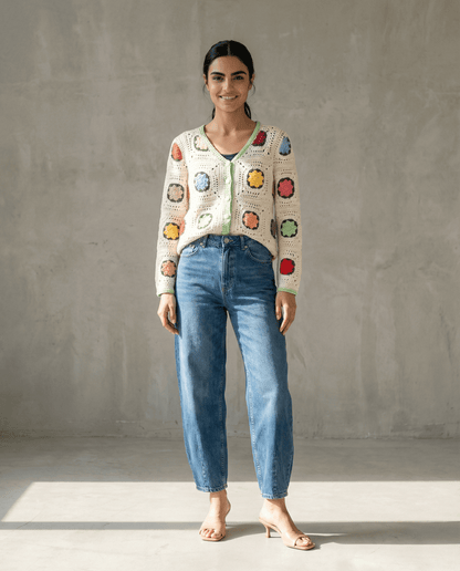 Handgemachte Strickjacke in buntem Patchwork-Design, kombiniert mit lässigen Jeans und Sandalen.