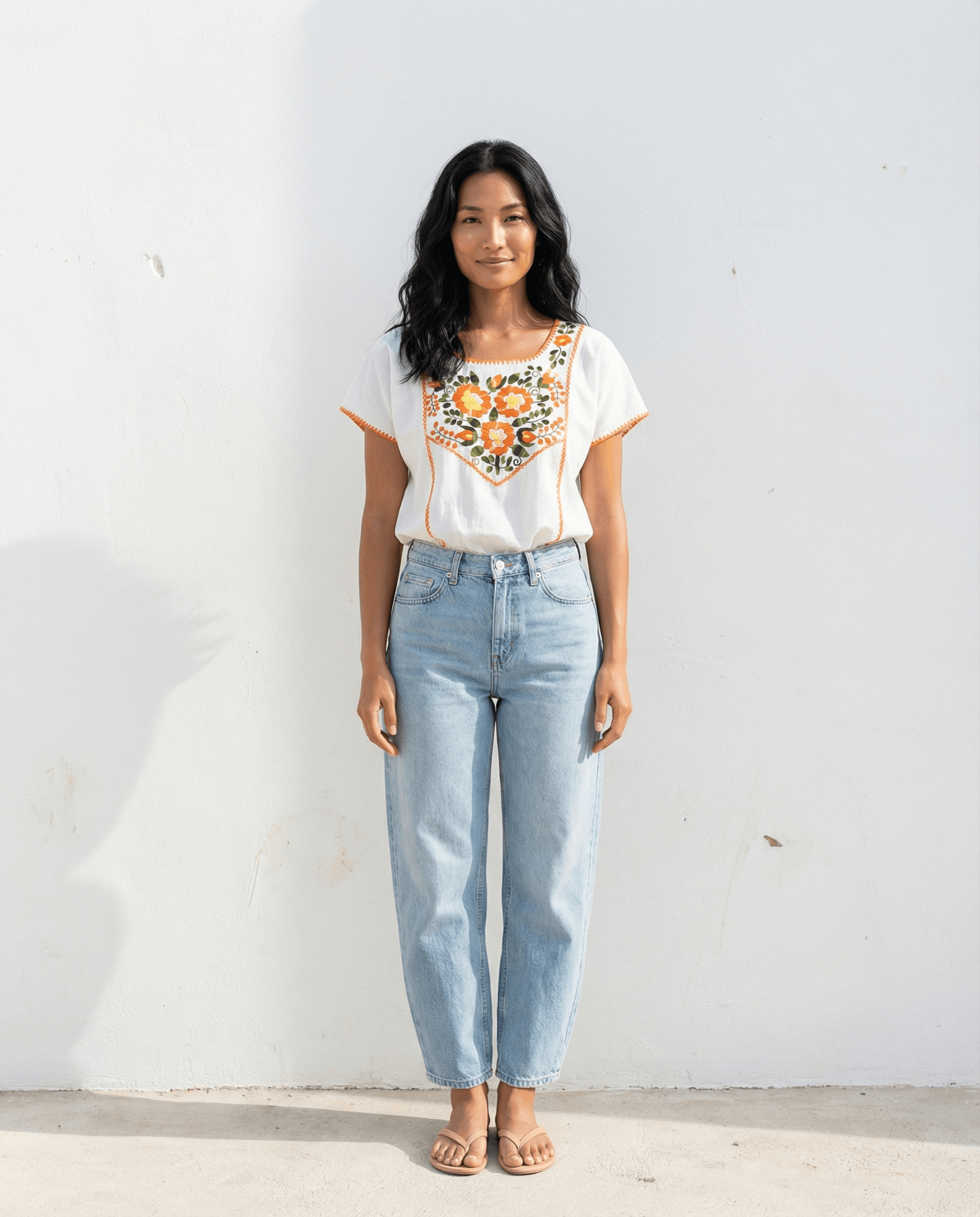 Handbestickte Carmela Bluse Nr. 15 – Creme/Orange getragen von einer Frau vor weißem Hintergrund.