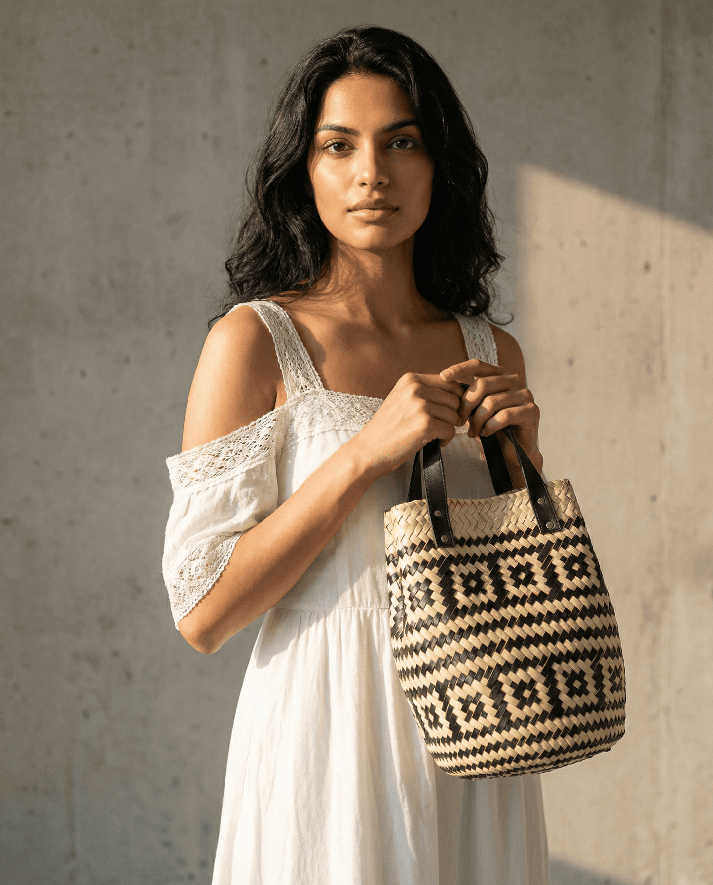 Frau mit Las Palmas Korb Tasche Klein vor grauem Hintergrund, elegant und stilvoll.