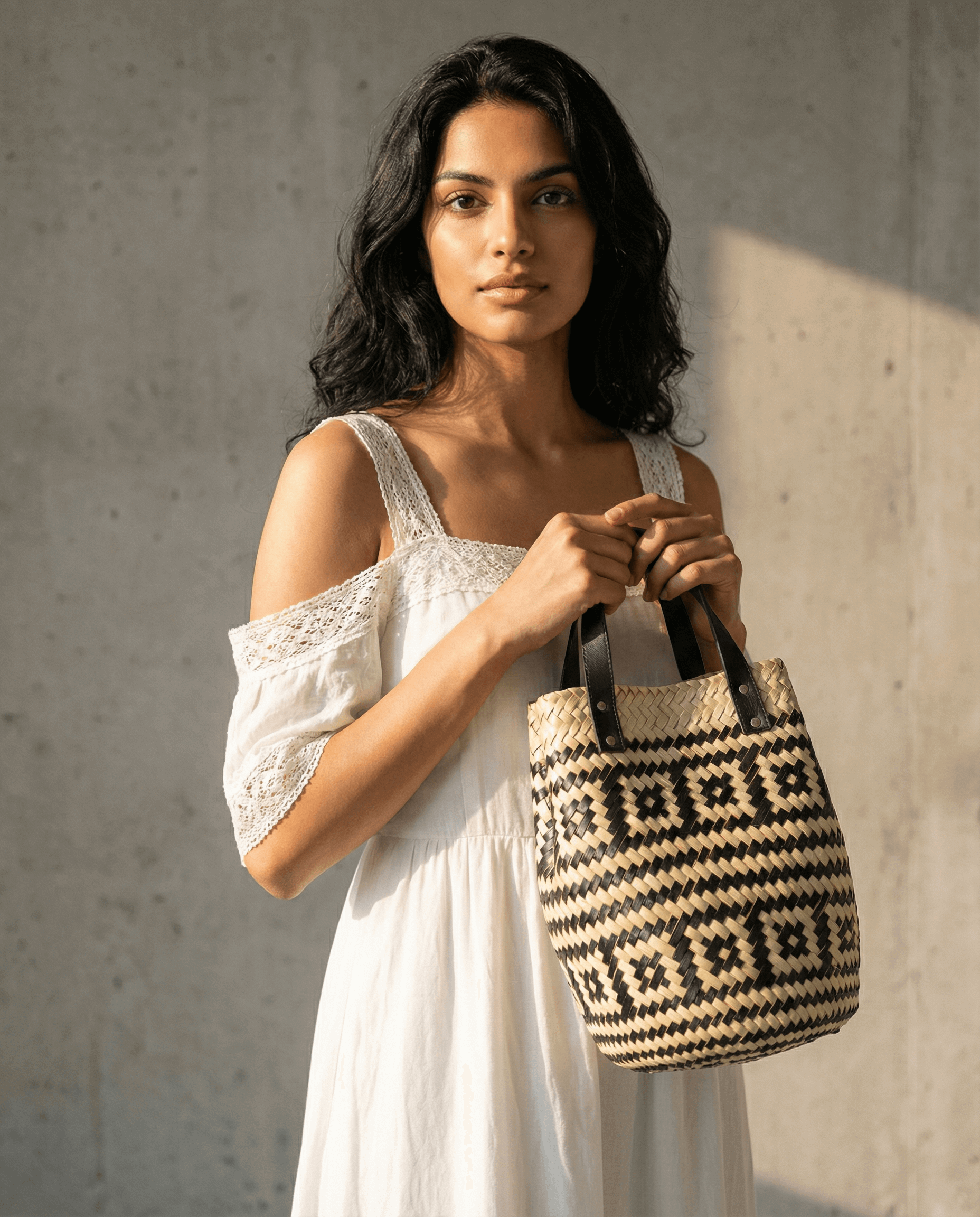 Frau mit Las Palmas Korb Tasche Klein vor grauem Hintergrund, elegant und stilvoll.
