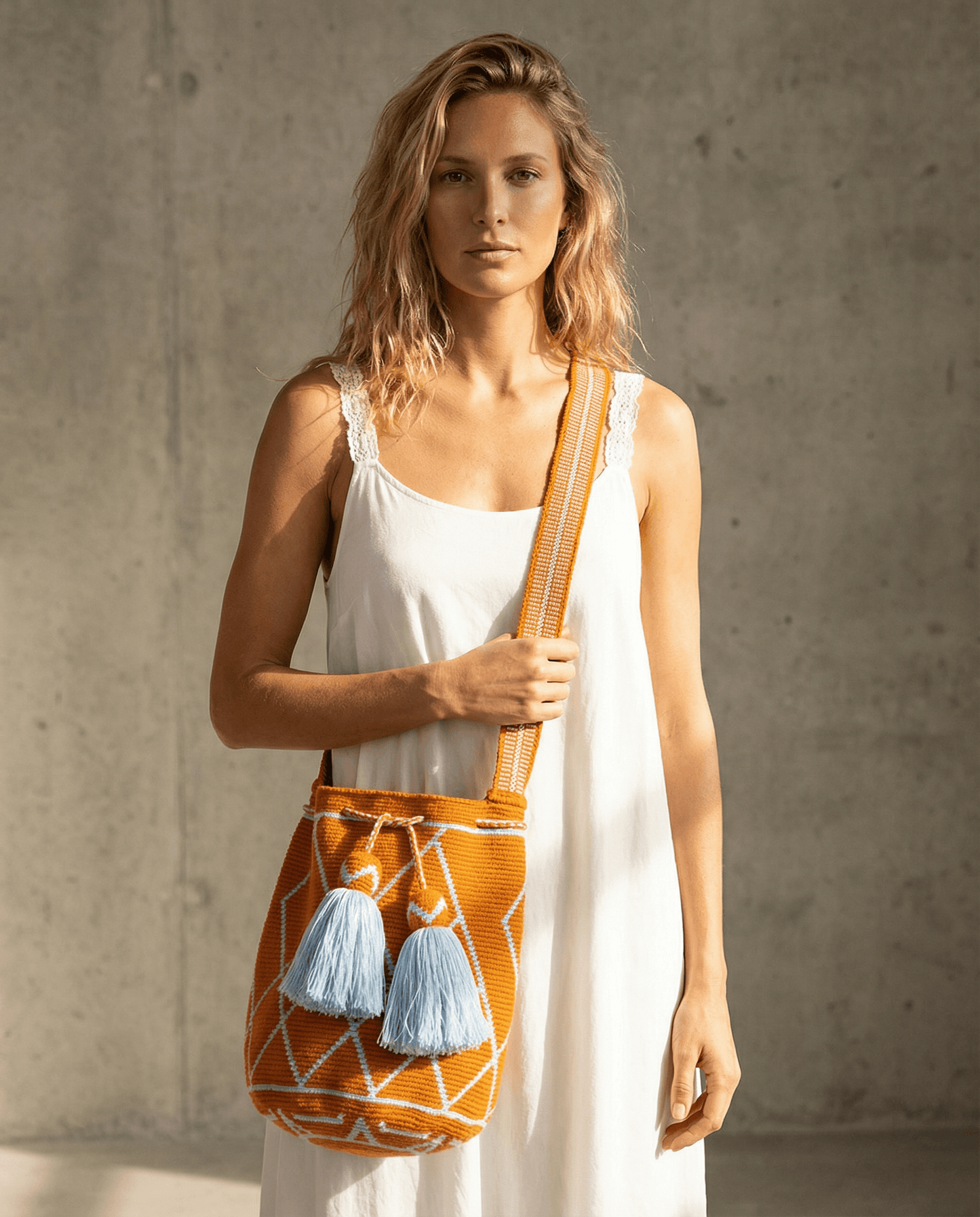 Wayuu Tasche Nr. 19 – Orange/Himmelblau, handgefertigt, präsentiert von Model vor neutralem Hintergrund.