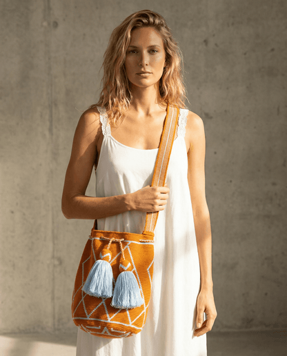 Wayuu Tasche Nr. 19 – Orange/Himmelblau, handgefertigt, präsentiert von Model vor neutralem Hintergrund.