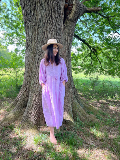 Frau im lila Midikleid Lucia unter einem Baum, passend für Alltag und Sommerabende.