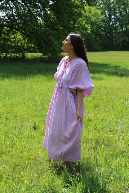Lucia Kleid in zartem Fliederton, ideal für alltägliche Anlässe, umgeben von einer blühenden Wiese.