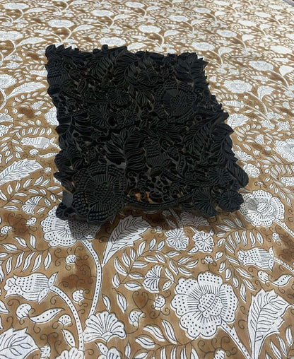 Detailaufnahme eines handgefertigten Blockdrucks auf einem braunen Stoff mit floralen Mustern.
